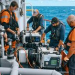 A diverse team of marine conservationists on a research vessel conducting marine life monitoring and tracking, exemplifying international cooperation for ocean conservation.