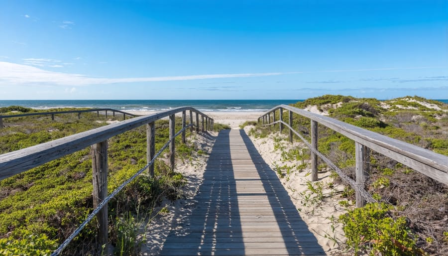 Wooden boardwalk winding through natural beach dunes with ocean in background