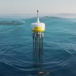 A surface ocean buoy with sensor cables and a nearby autonomous underwater vehicle monitoring the water in clear blue ocean conditions.
