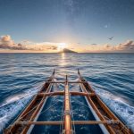 Traditional Polynesian double-hulled canoe sailing on open water at dawn beneath a twilight sky with visible stars and seabirds in flight.